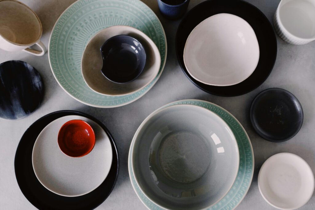 Top view of a variety of ceramic plates and bowls in an artistic arrangement showcasing modern tableware design.
